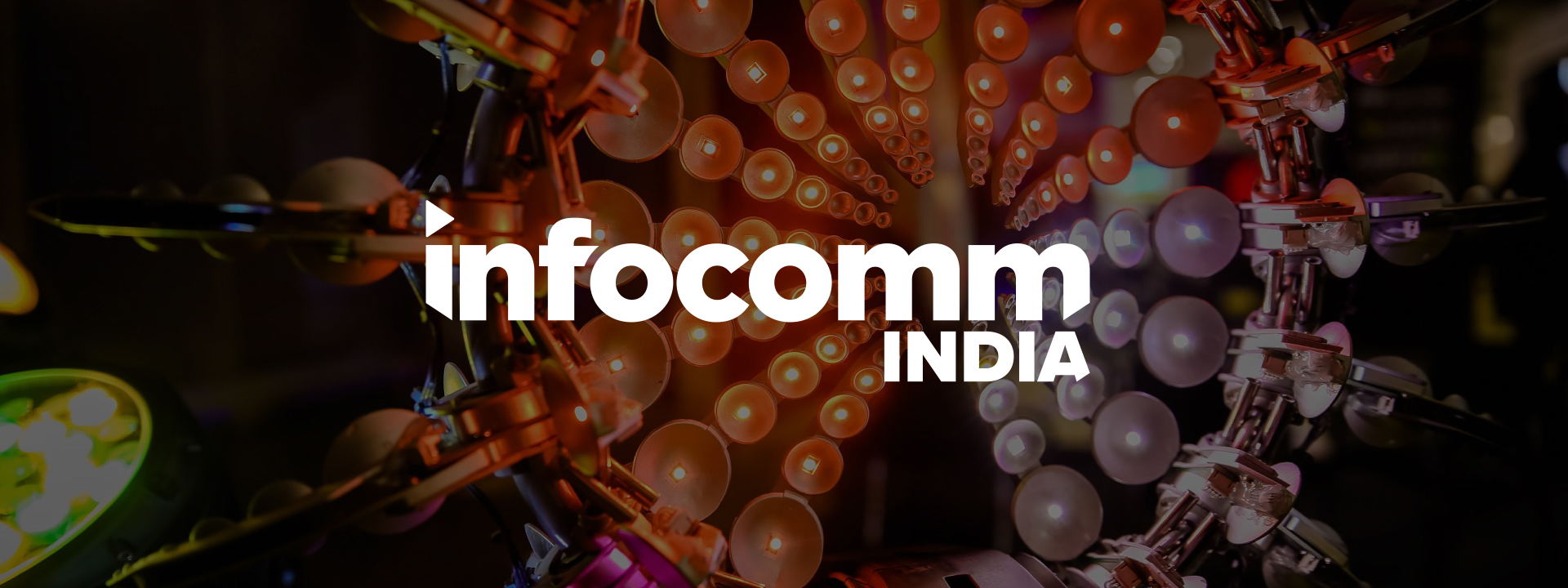A vibrant display of multicolored lights in a circular pattern, with the words infocomm INDIA in bold white lettering at the center.