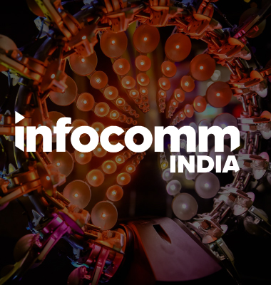 A vibrant display of multicolored lights in a circular pattern, with the words infocomm INDIA in bold white lettering at the center.