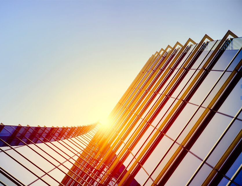 Sunlight reflecting off the glass surface of a modern skyscraper, with a curved architectural design.